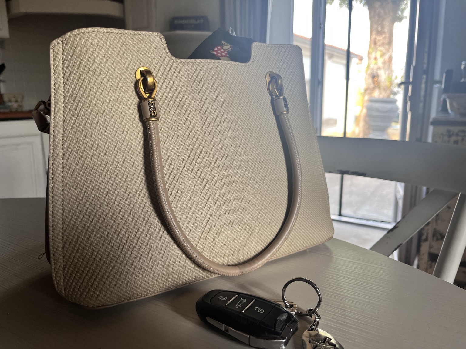 A small folded shopping bag tucked inside a handbag beside car keys