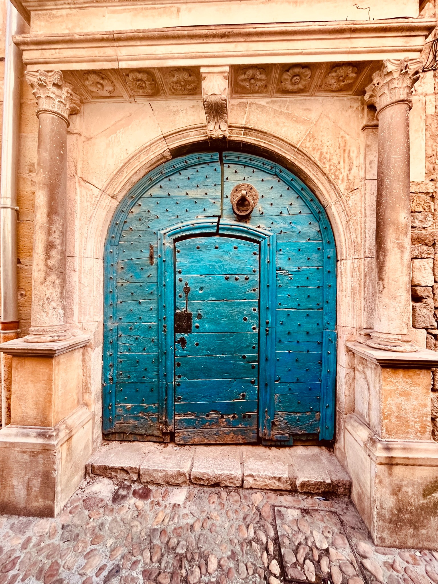 Weathered turquoise French door in an old stone surround