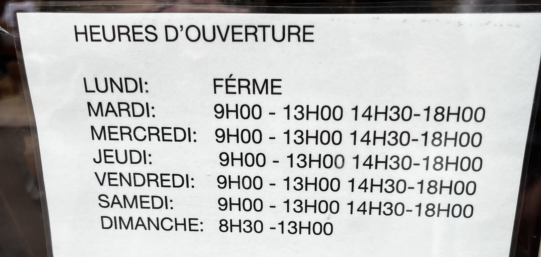 French opening-hours notice showing Monday closed, split daytime hours and Sunday morning opening
